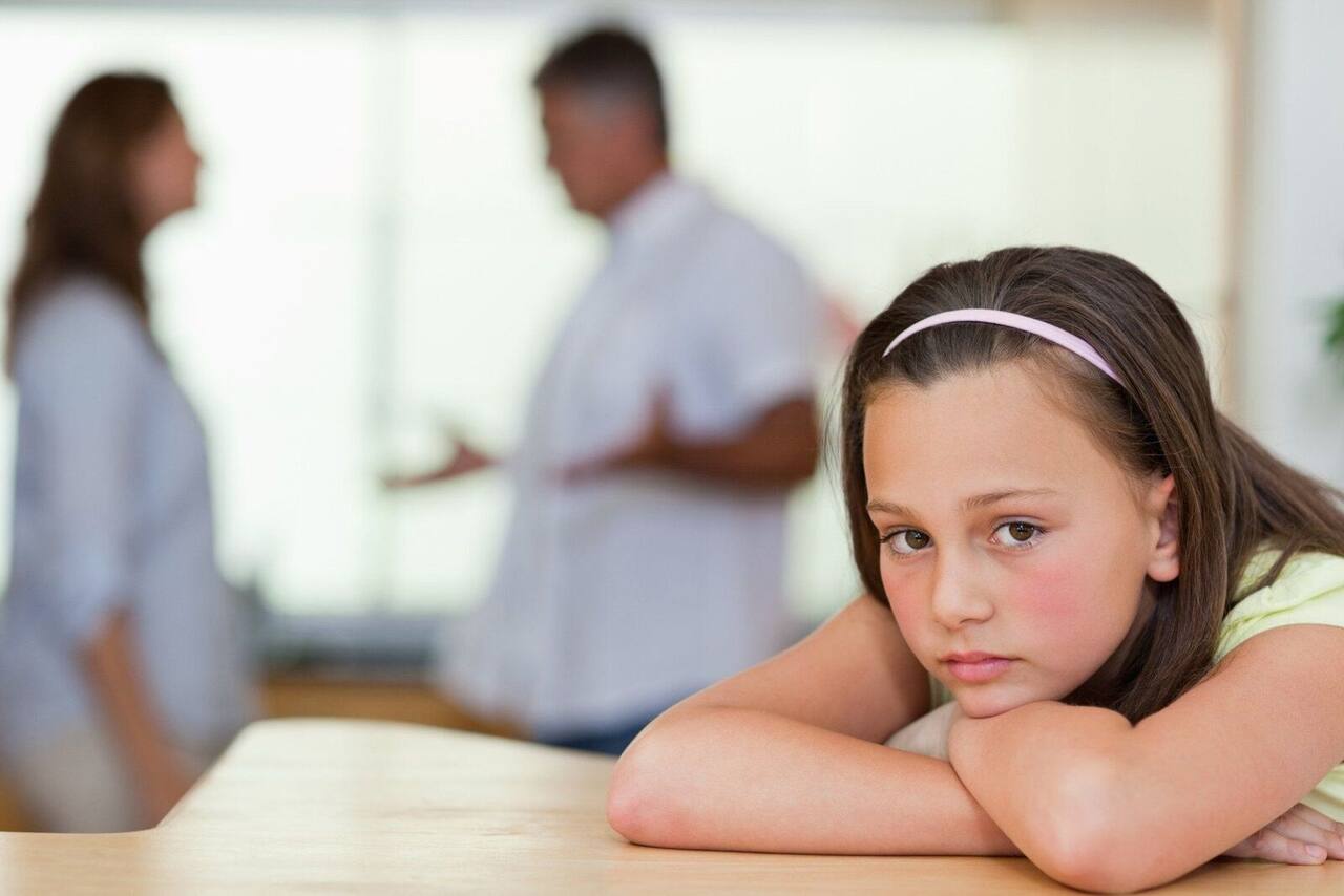 Child at a table while parents talk in the background