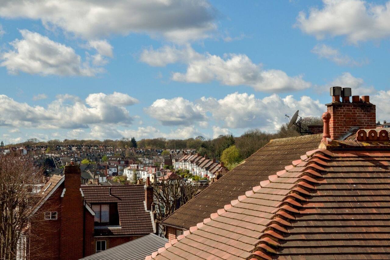 Rooftops of terraced houses beneath a blue sky