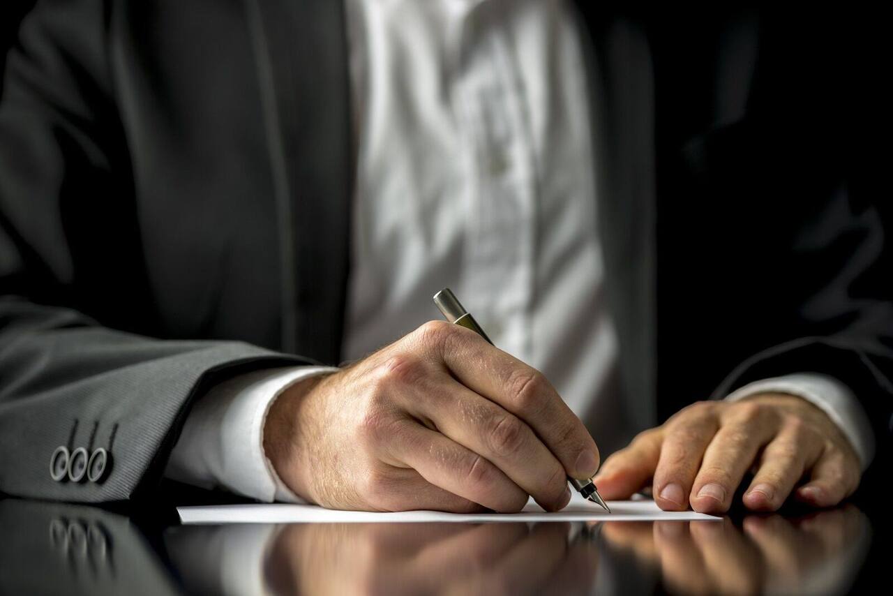 Hand signing a document with a pen